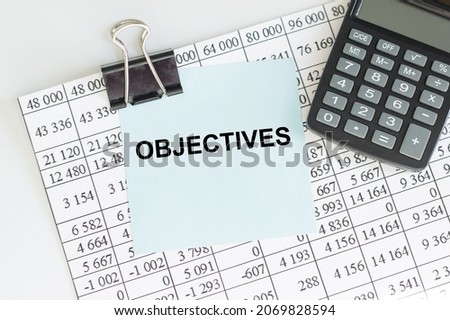 text Objectives on a card held on a clip by a sheet of paper with numbers. Financial concept