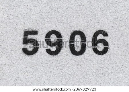 Black Number 5906 on the white wall. Spray paint. Number five thousand nine hundred six.