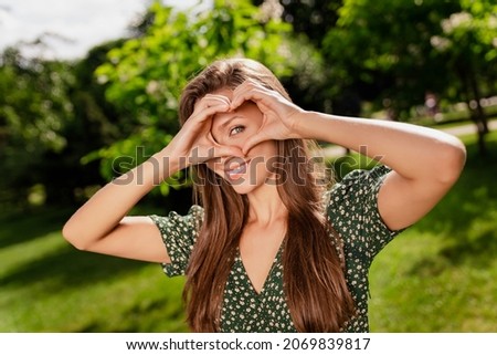 Photo of affectionate lovely lady make heart symbol cover eye wear green dress nature park garden outdoors