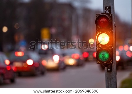 city crossing with a semaphore on blurred background with cars in the evening streets, orange light Royalty-Free Stock Photo #2069848598