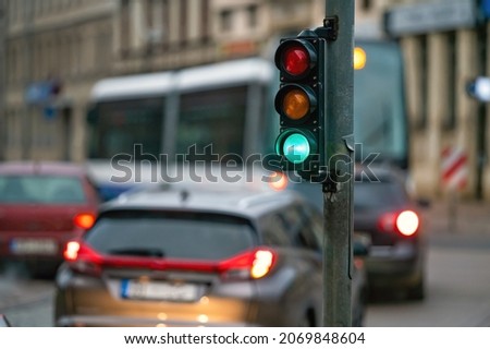 a city crossing with a semaphore on blurred background with cars in the evening streets, green light