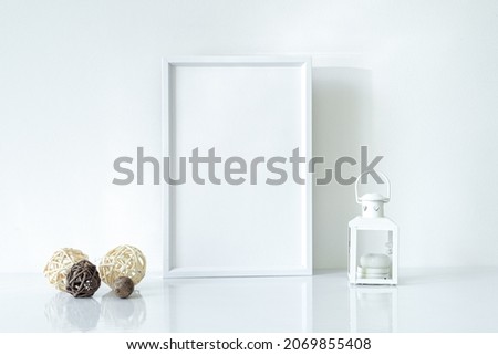 Mock up white frame with Christmas lantern and decorations on shelf. Portrait frame against a white wall