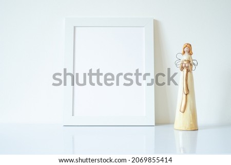 Vertical white blank frame mockup with porcelain Christmas angels. Wedding scene. Christmas, Valentine's day concept. Copy space.