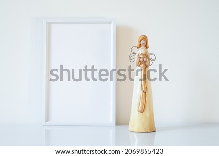 Vertical white blank frame mockup with porcelain Christmas angels. Wedding scene. Christmas, Valentine's day concept. Copy space.