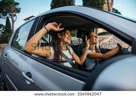 Two young women sing a song on the radio and dance in the car on a day trip in the summer - Best friends having fun together driving around the countryside - Smiling millennial in a relaxing moment Royalty-Free Stock Photo #2069862047