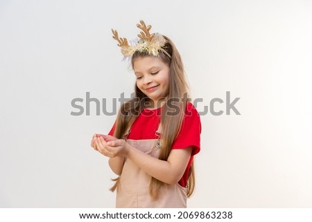 A little girl with Christmas horns is holding a little surprise in her hands.