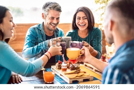 People group toasting latte at coffee bar rooftop - Friends talking and having fun together at cappuccino restaurant - Life style concept with happy men and women at cafe terrace - Bright warm filter Royalty-Free Stock Photo #2069864591