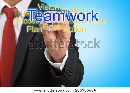 businessman drawing word teamwork on blue background
