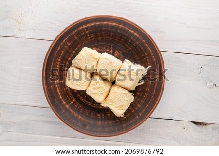Several delicious cotton candy on a clay dish on a wooden table, close-up, top view.