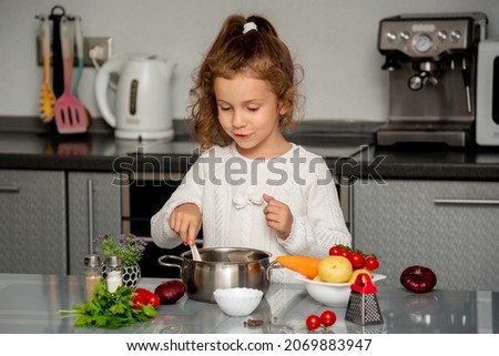 A little pretty girl cooks in the kitchen from fresh vegetables. Conceptual photography. Proper nutrition. Diet.