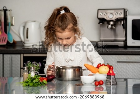 A little pretty girl cooks in the kitchen from fresh vegetables. Conceptual photography. Proper nutrition. Diet.