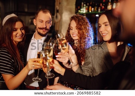 Group of friends partying in a nightclub and toasting drinks with champagne. Happy people enjoying winter holiday. Party, celebration, drink, birthday concept.