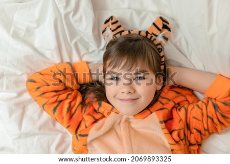 child smiling girl 9 years old with dark hair in a tiger costume as a symbol of 2022 close-up looks at the camera. High quality photo
