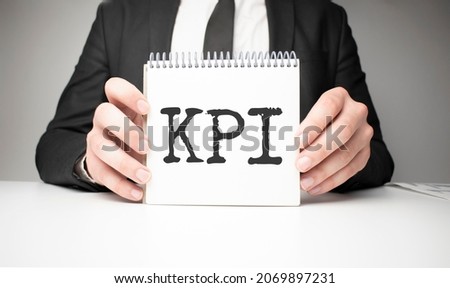 Businessman holding sheet of paper with a message KPI