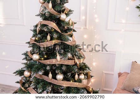 The tree is decorated with colorful toys and a garland. Close-up photo in warm colors. Christmas and New Year atmosphere