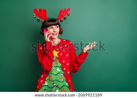 Photo of cute charming woman dressed red pullover antlers talking modern device looing empty space isolated green color background