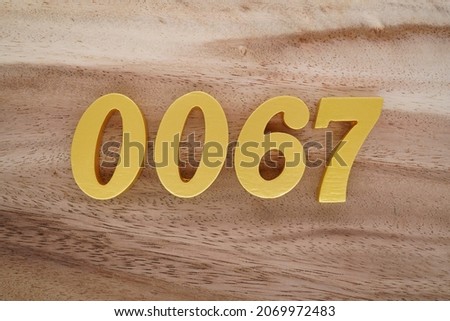 Golden Arabic numerals 0067 on a dark brown to white wood grain background.