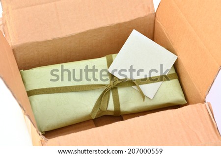 Olive green gift box with dark green ribbon and bow with gift card inside a cardboard delivery box.Concept photo of birthday, holidays, life events, wedding and special occasion