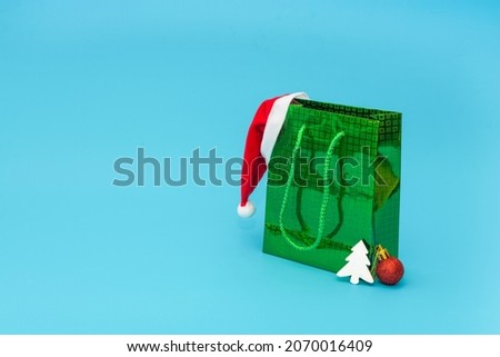 Green bag with gifts and Santa Claus hat for Christmas or New Year. Holiday gifts shopping concept.