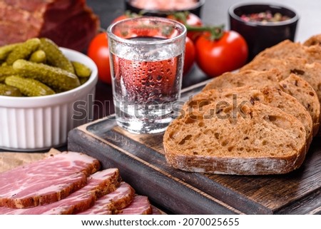 Delicious fresh bacon sliced with bread and vegetables on a dark concrete background