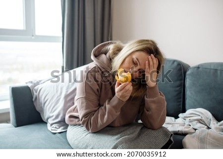 Long covid syndrome - increased fatigue, lack of strength, reduced immunity, memory problems and anosmia - loss of smell. Woman sniffs citrus fruits and does not smell Royalty-Free Stock Photo #2070035912