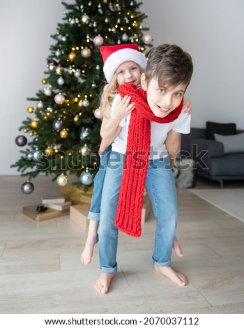 Children - a boy and a girl are playing near the Christmas tree. Living room interior with Christmas tree and decorations. New Year. Gift giving.