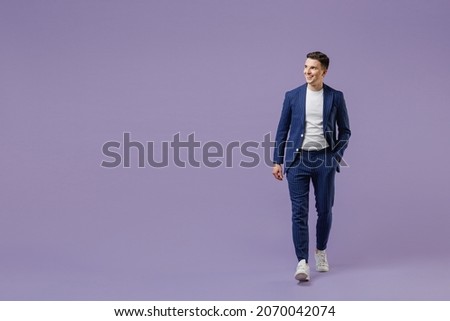 Full size fun young successful employee business man lawyer 20s wears formal blue suit white t-shirt work in office move hand in pocket look aside isolated on pastel purple background studio portrait Royalty-Free Stock Photo #2070042074