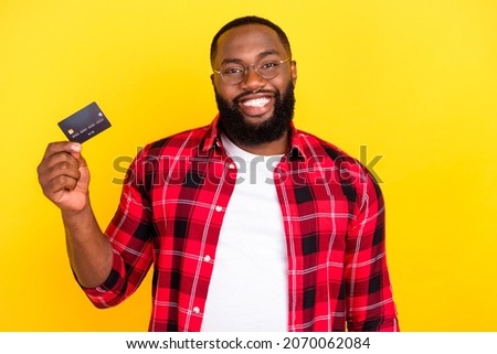 Photo of positive happy young man hold hand credit card smile isolated on yellow color background