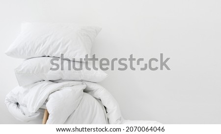 Laundry day and hotel service concept. Banner view of clean duvet and fresh pillows against white copy space background. Part of bedding on chair in apartment with comfort bedroom Royalty-Free Stock Photo #2070064046