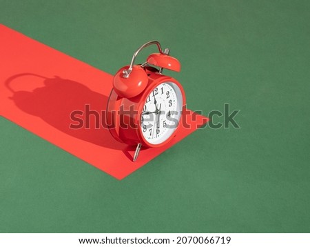 red retro clock and red paper with copy space against pastel green background. abstract art. minimalism