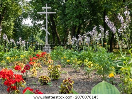 an Orthodox cross on a pedestal. advertising picture. flower alley. a symbol of faith.