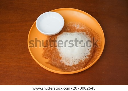 A picture of "apom lenggang" with sweet milk on plate. Traditional food made of cold rice, coconut milk, flour and sugar.