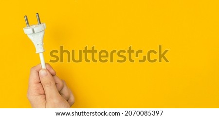 Electrical power cable in hand, banner. Orange background, flat lay, top view and copy space