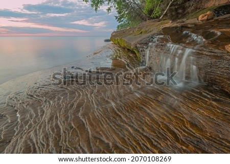 Landscape near sunset of a waterfall and the eroded sandstone shoreline at Miner's Beach, Lake Superior, Pictured Rocks National Lakeshore, Michigan's Upper Peninsula, USA