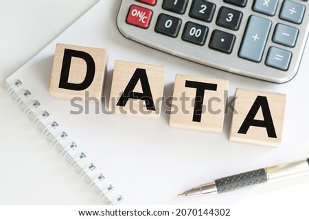 DATA word written on wooden cubes on the background of a notepad on the table next to a calculator and a pen on the table