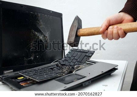 The man destroyed laptop with a hammer. Nervous work, buggy computer, errors, slow Internet, not saved in the game, printed text, hung. Bad old computer failed, does not turn on, keyboard Royalty-Free Stock Photo #2070162827