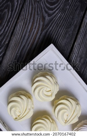 Homemade yellow marshmallow with lemon and ginger. Against a background of black pine boards.