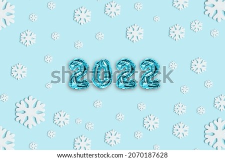2022 blue foil balloons decor and Christmas snow with copy space on blue background. New Year concept