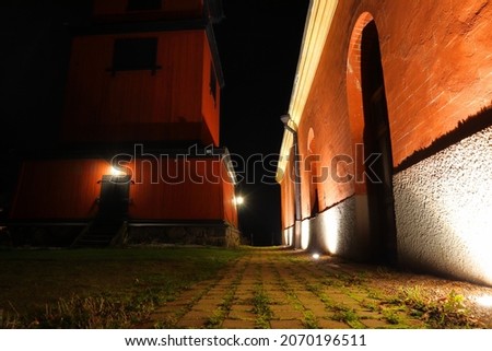 Skokloster, Sweden. Part of the old church brick wall at night. Dark background. Lamp shining in the evening. Outside of Stockholm, Scandinavia, Europe.