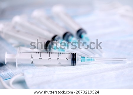 Five medical syringes are on the table. Disposable syringes and medical masks. Consumables for injection and virus protection. Horizontal photo.  Royalty-Free Stock Photo #2070219524
