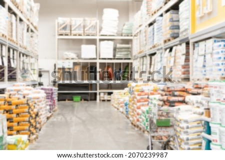 Hardware construction supermarket aisle and shelves with bags of cement and plaster mix for leveling the floor and walls. Blurred shopping background. Royalty-Free Stock Photo #2070239987