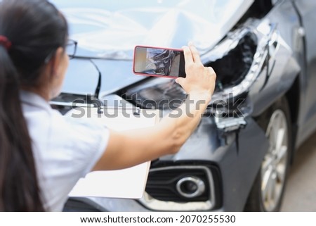 Woman insurance agent taking pictures of broken car on mobile phone closeup. Estimating cost of vehicle damage concept