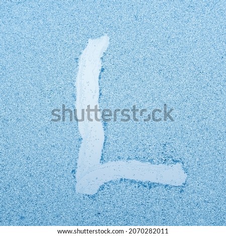 The letter L written on glass with frost in the frost in winter, close up. Royalty-Free Stock Photo #2070282011