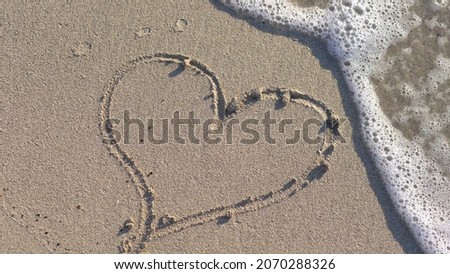 Woman Drawing a Heart on the Sand at Sunset