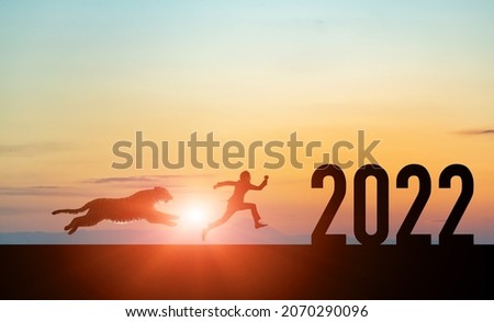 2022 New Year concept. Silhouettes of running man and tiger.