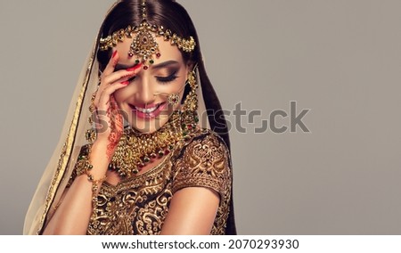 Portrait of beautiful indian girl. Young hindu woman model with golden kundan jewelry set . Traditional Indian costume lehenga choli . Royalty-Free Stock Photo #2070293930