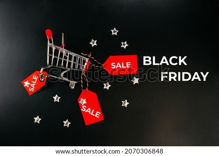 Creative design.Copy space.Shop trolley at supermarket. Sale, discount, shopaholism concept.Black Friday Super Sale.Black Friday shopping sale concept with red ticket Sale tag on black background.