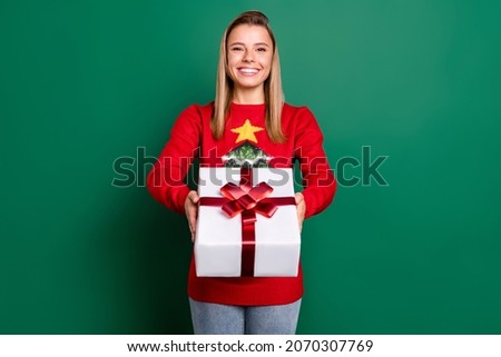 Portrait of attractive cheerful blonde girl holding giftbox tradition isolated over green color background