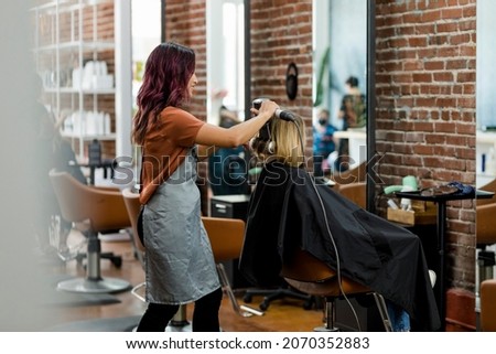 Hairstylist giving a haircut to a customer at a beauty salon Royalty-Free Stock Photo #2070352883