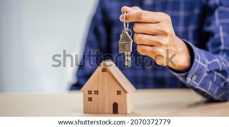 Businessman choosing mini wood house model from model and row of coin money on wood table, selective focus, Planning to buy property.Choose what's the best. A symbol for construction ,ecology, loan co